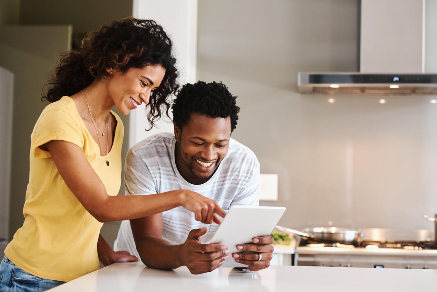 Pareja sonriendo y señalando una tablet.